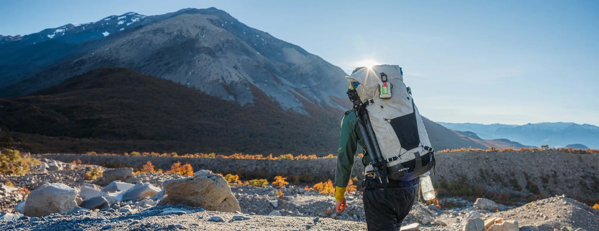 A hiker carrying a ZOLEO-equipped backpack in the mountains